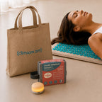 Le sac de transport Climsom Zen, la boîte du ZenSpire + et le ZenSpire + allumé, devant une femme allongée sur le tapis d’acupression